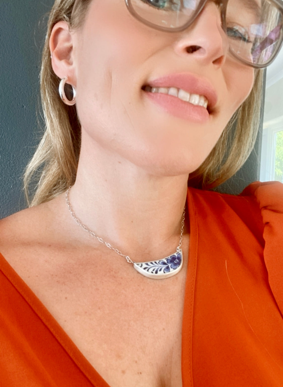 Smiling woman in a red blouse wearing classic sterling silver hoop earrings, adding a touch of chic to her ensemble.