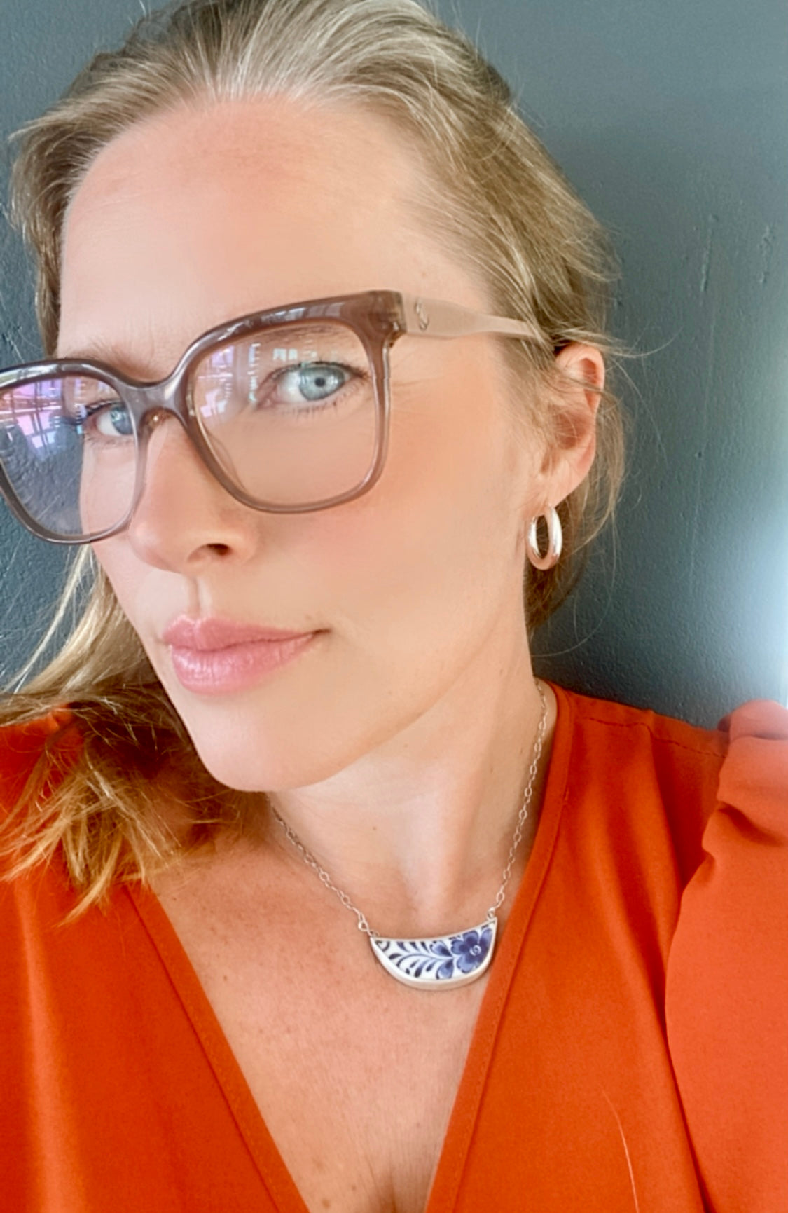 Woman with glasses wearing sterling silver hoops, complementing her smart and sophisticated look