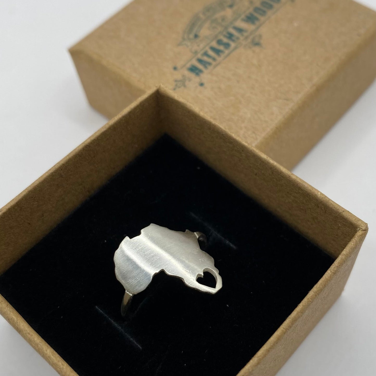 Silver ring with a unique design in a brown box on a white background