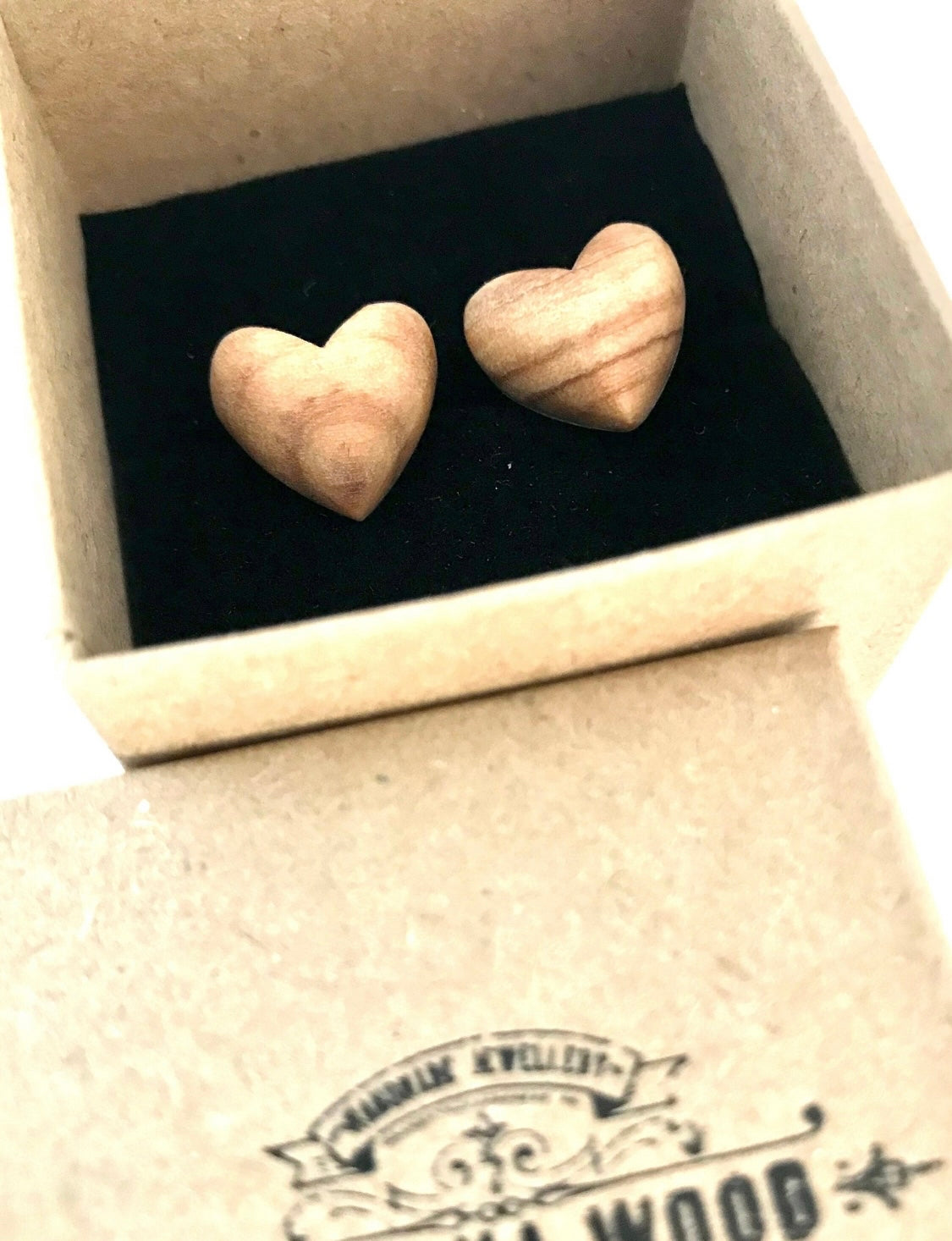 Hand carved heart stud earrings nested in a branded presentation box, ready for gifting.