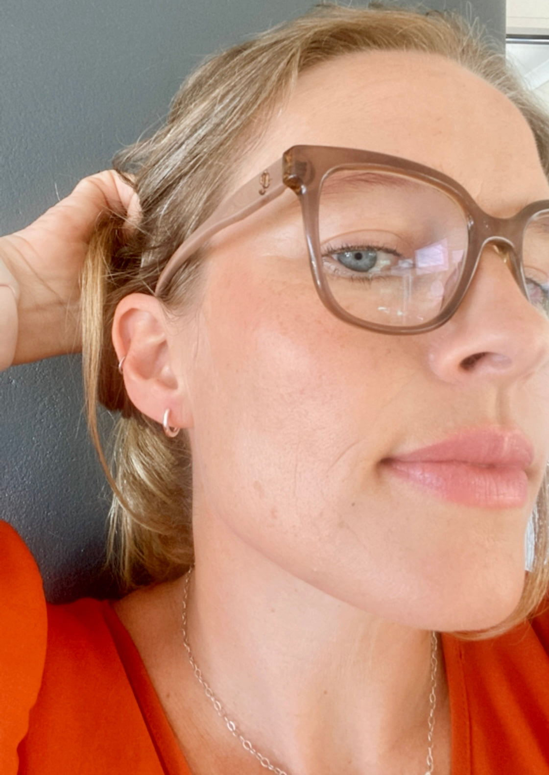 Woman smiling, wearing small sterling silver hoops, showcasing their everyday appeal