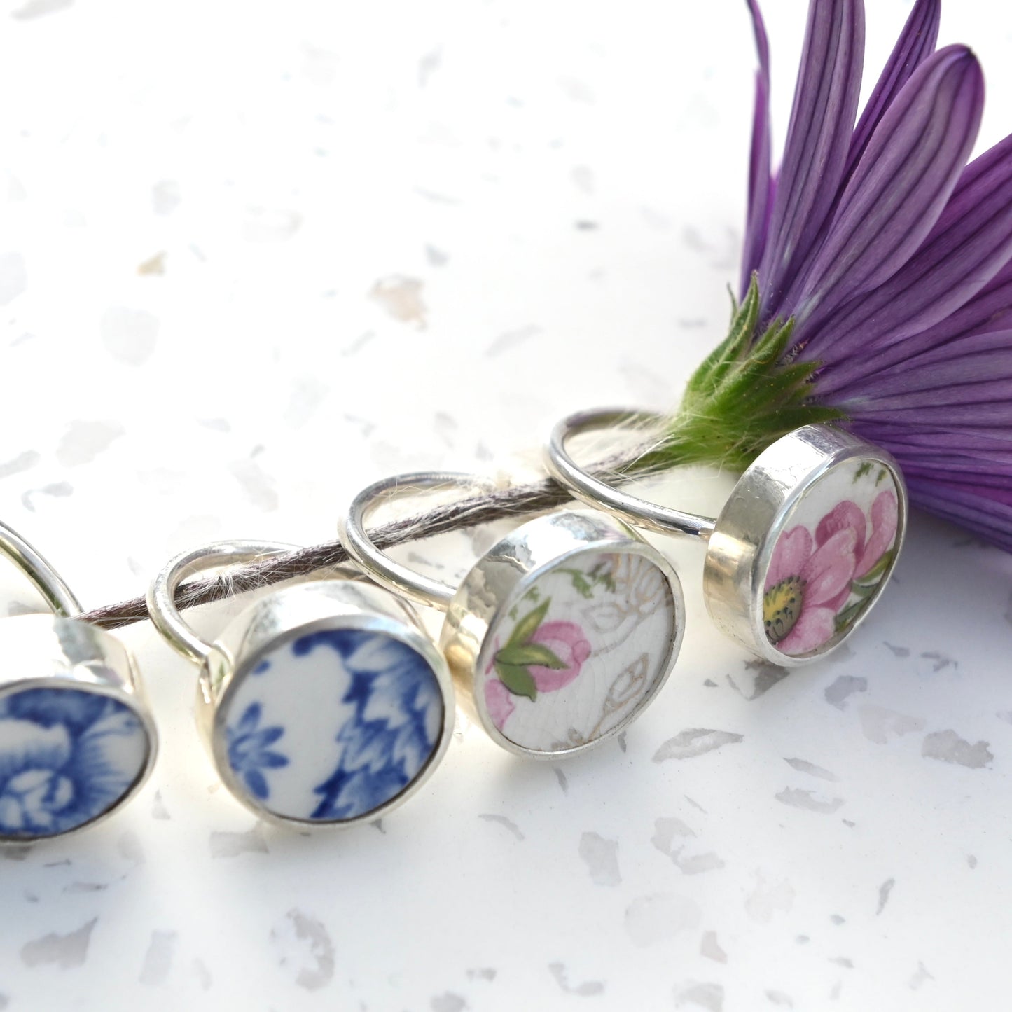 Set of floral-themed rings on a white surface with a purple flower.