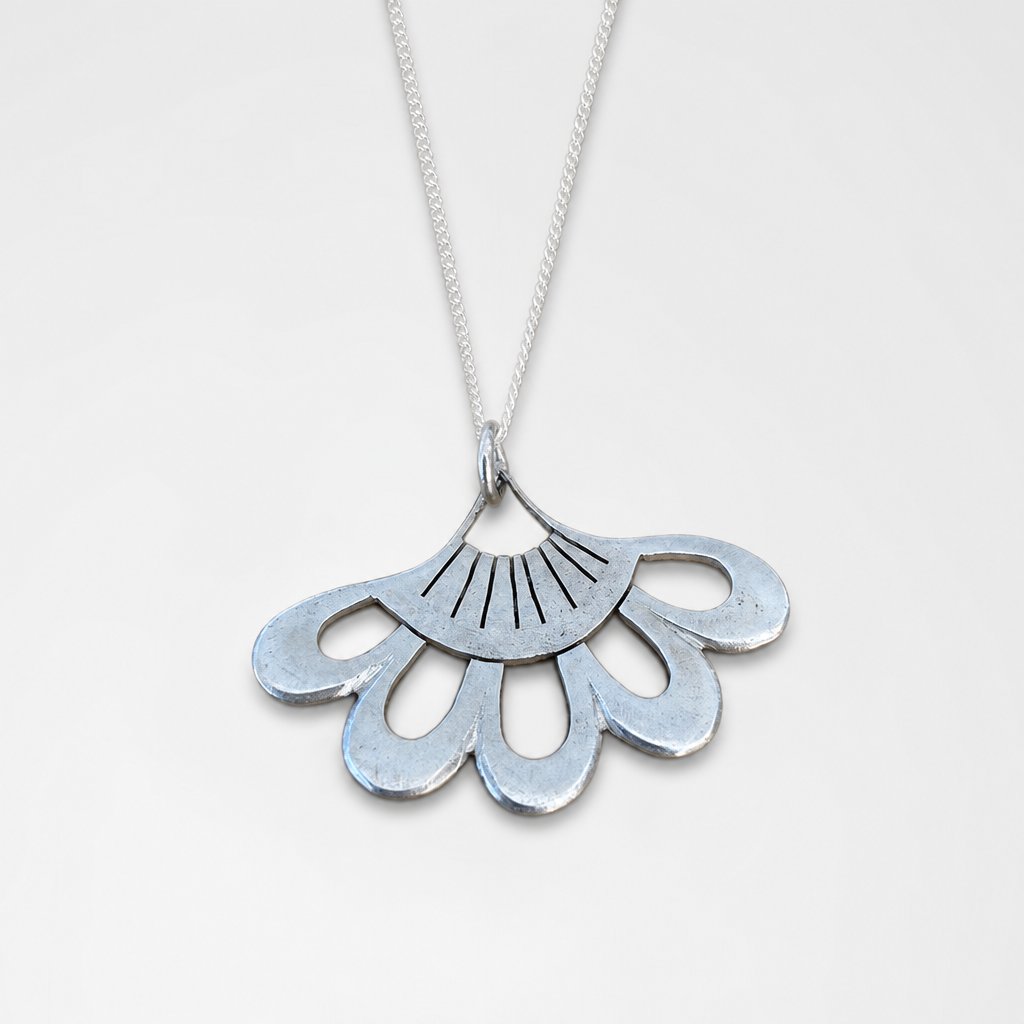 Lotus Flower Pendant - close-up of sterling silver hand-pierced detail on natural wood surface - Natasha Wood Jewellery
