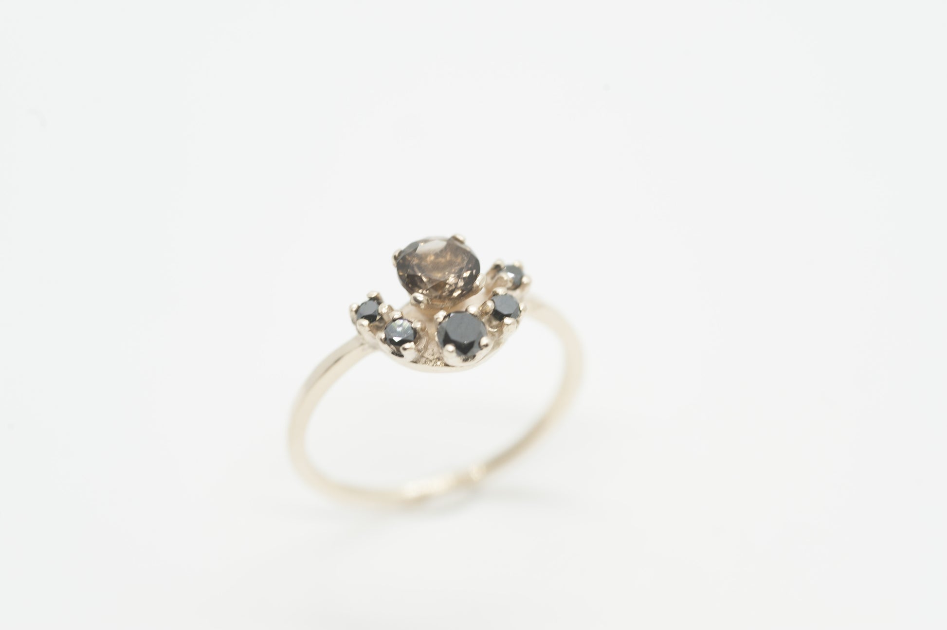 Elegant custom gold ring with smokey quartz centerpiece and black diamonds displayed on a clean white surface