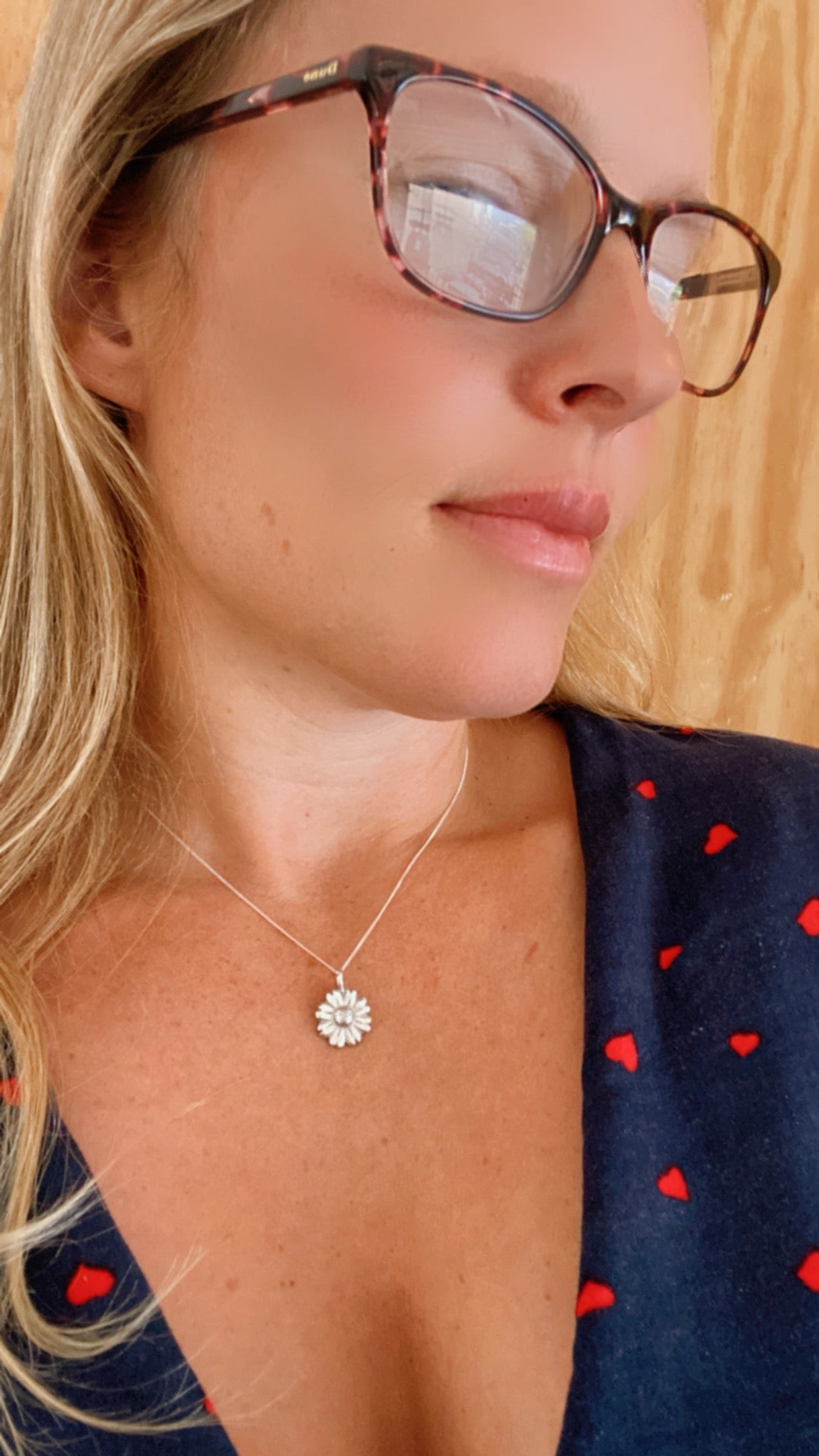Woman wearing a sterling silver Daisy Flower pendant, exemplifying its wearability and elegance.
