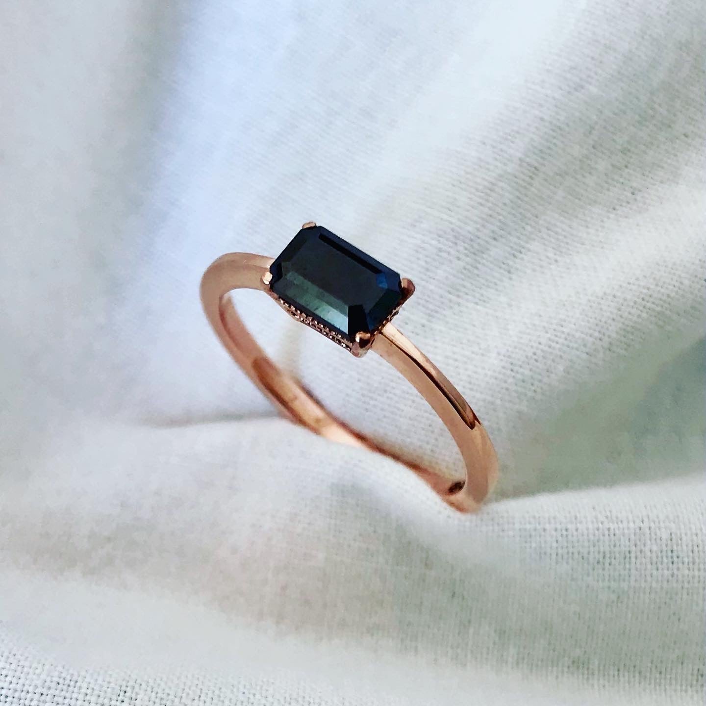 "Image showcasing a bespoke rose gold ring with a central black diamond, presented against a soft white fabric background, highlighting the ring's refined elegance and the gemstone's deep hue.
