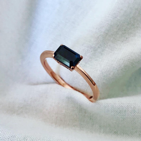 "Image showcasing a bespoke rose gold ring with a central black diamond, presented against a soft white fabric background, highlighting the ring's refined elegance and the gemstone's deep hue.