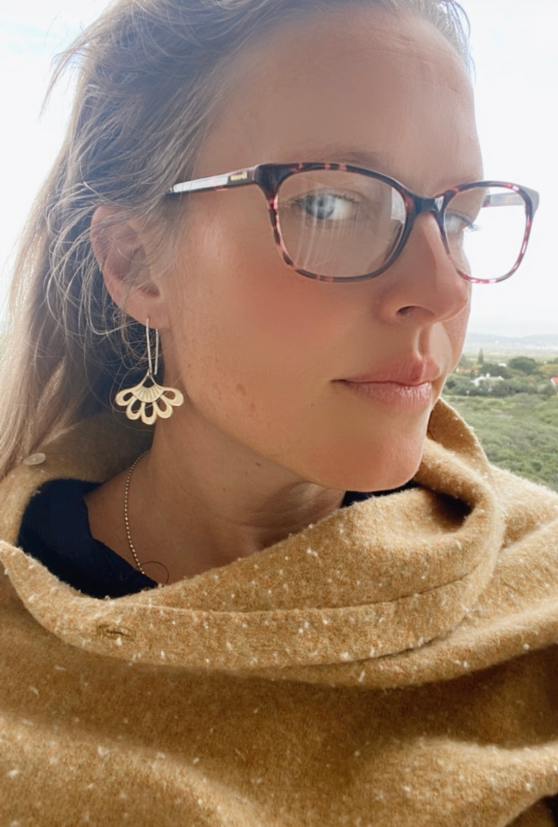 a women wearing Elegant lotus hook earrings in silver, pictured from a side angle to highlight the curvature and craftsmanship.