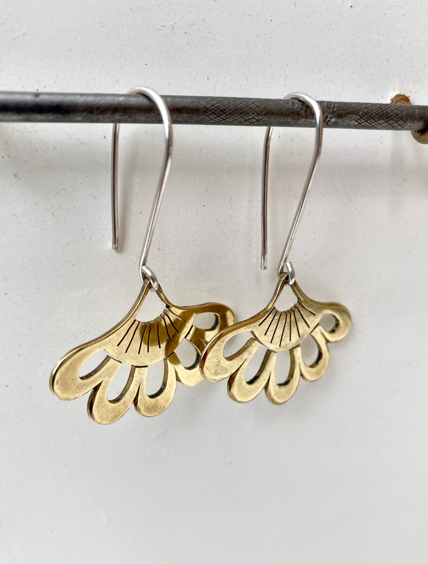 Elegant lotus hook earrings in silver, pictured from a side angle to highlight the curvature and craftsmanship.
