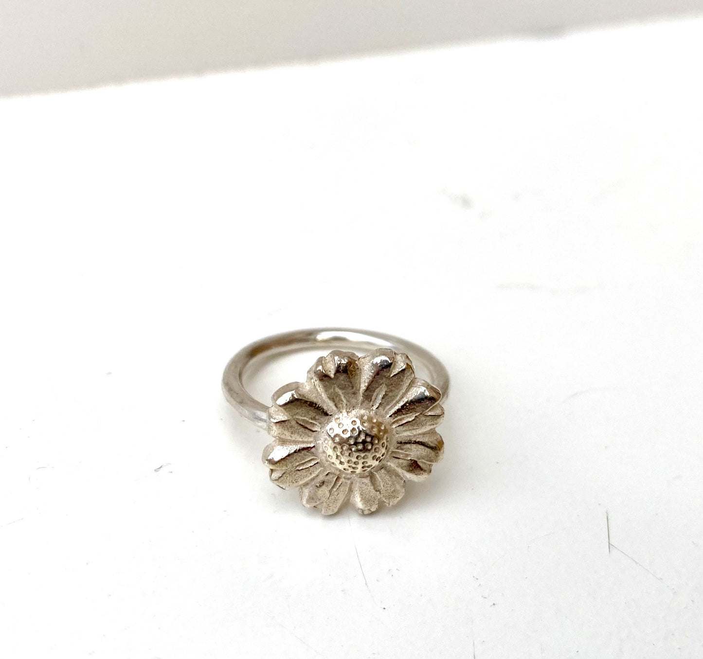 Close-up of the oxidised Daisy Flower Ring next to a brass and silver variation, highlighting the textural contrast.