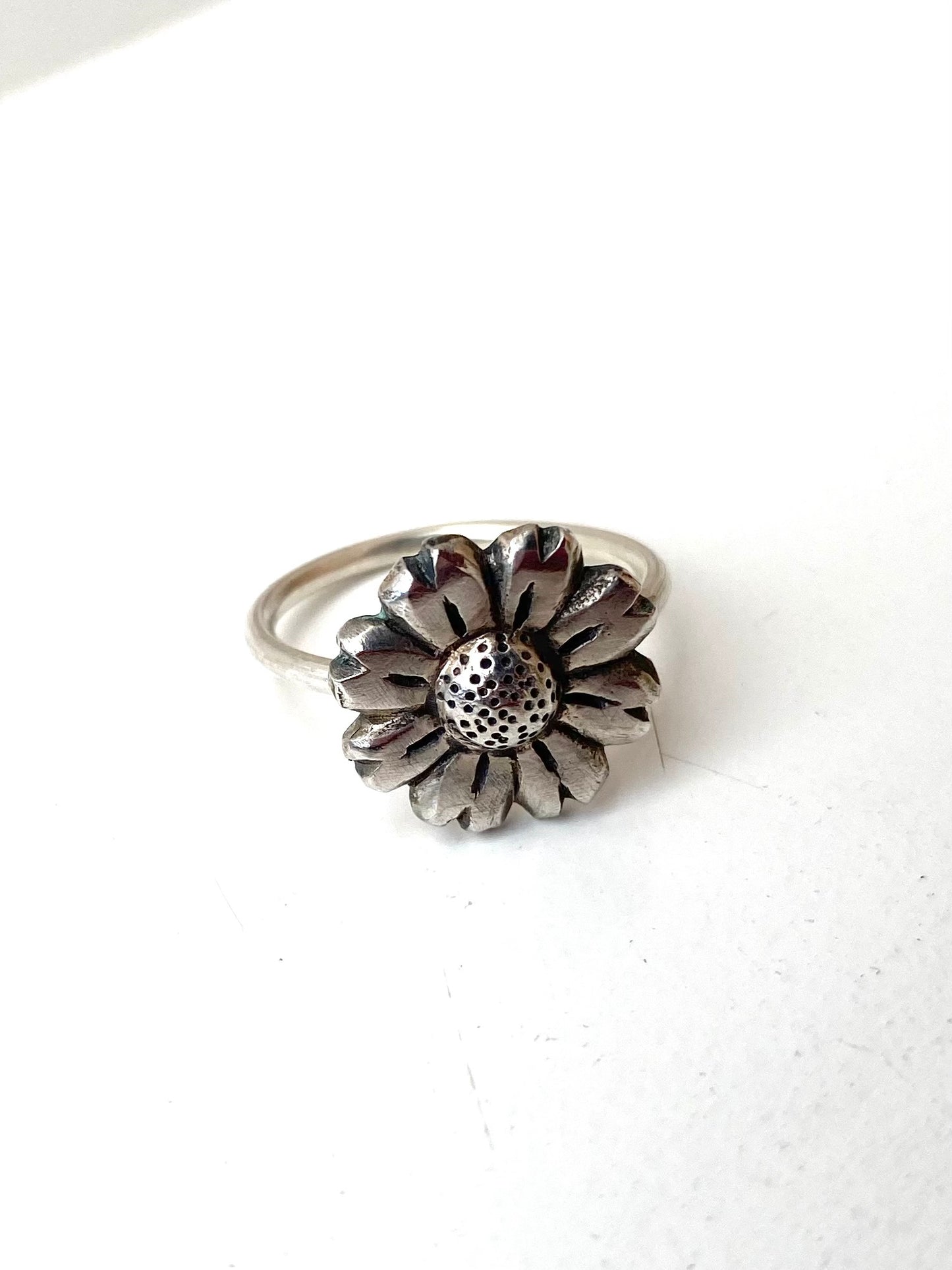 Close-up of the oxidised Daisy Flower Ring next to a brass and silver variation, highlighting the textural contrast.