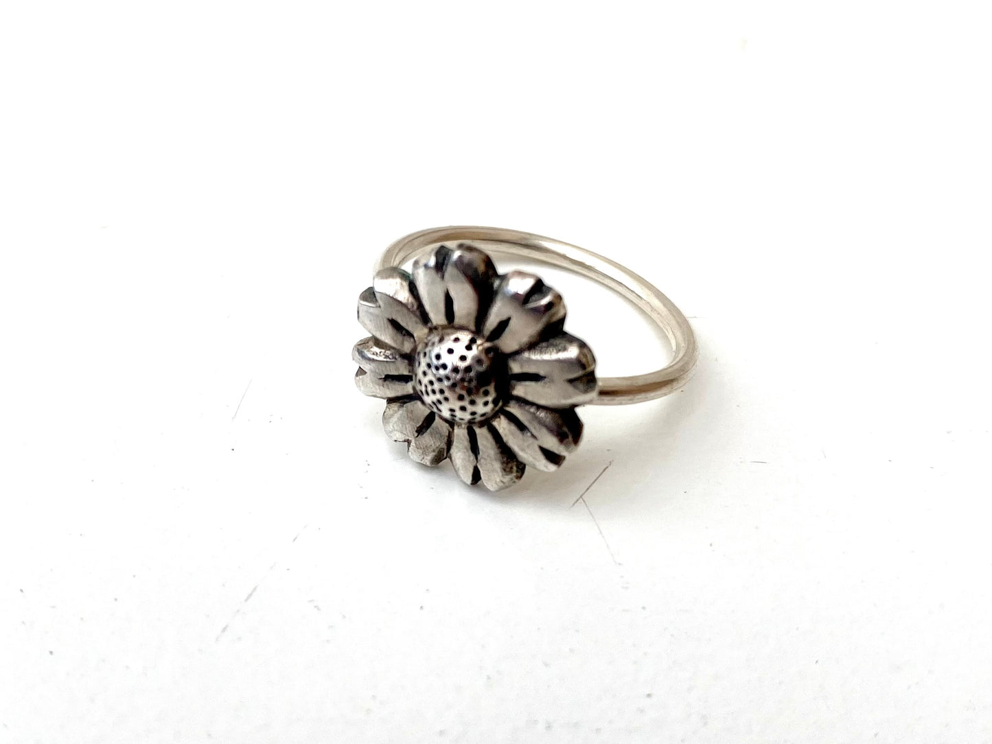 Close-up of the oxidised Daisy Flower Ring next to a brass and silver variation, highlighting the textural contrast