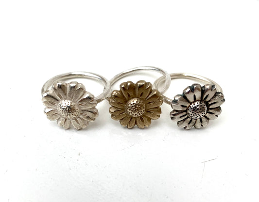 Variety of Daisy Flower Rings in brass, oxidised, and plain silver on display, demonstrating different color options.