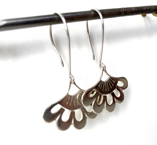 Sterling silver lotus earrings showcased on a white surface, emphasizing their intricate cut-out design and polished finish.