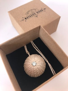 Handcrafted sea urchin pendant with a blue gemstone centerpiece presented in a branded Natasha Wood Jewellery box