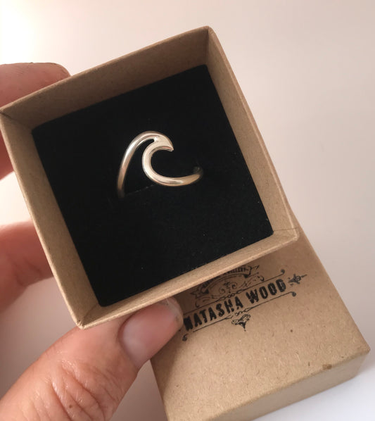Hand holding a box with a sterling silver wave ring, reflecting a sleek, ocean-inspired design, by Natasha Wood Jewellery