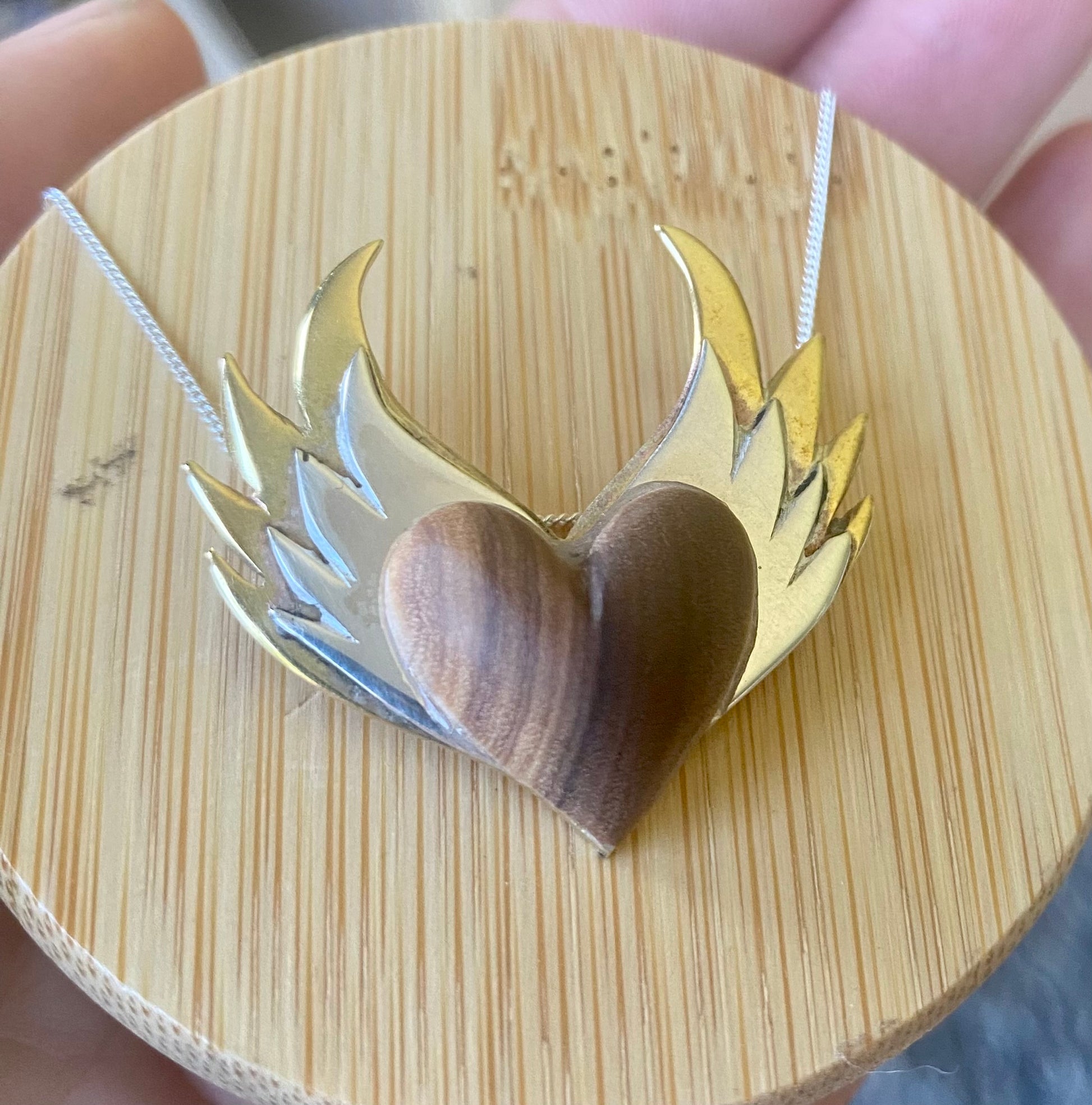 Side view of the silver-winged wooden heart pendant showing the depth and craftsmanship