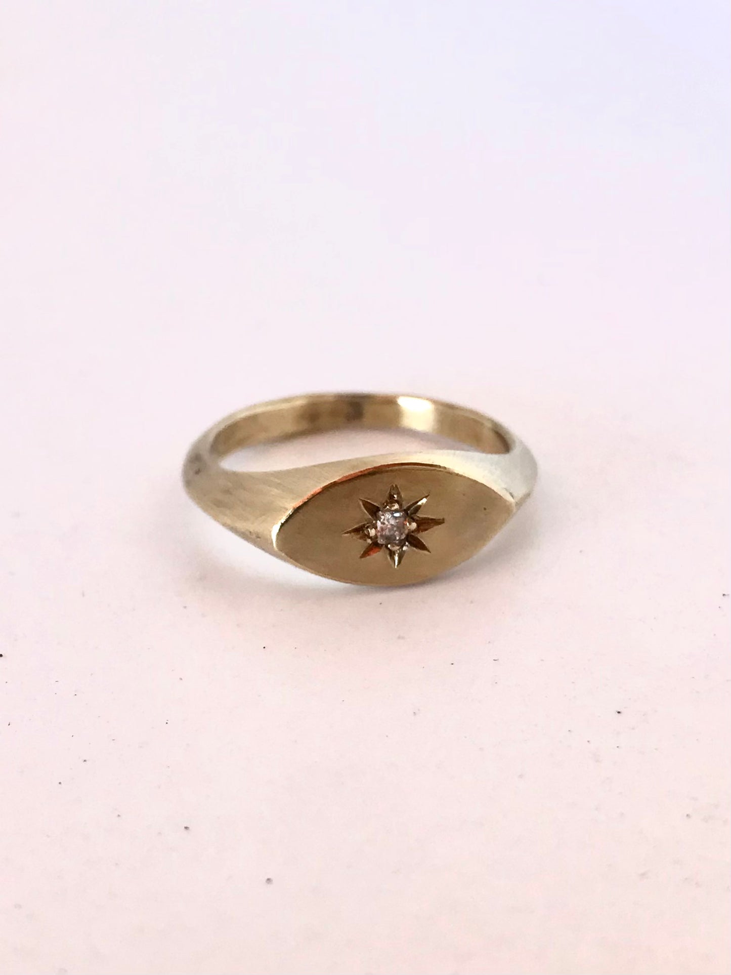 Angle view of the brass signet ring on a light surface, highlighting the topaz gemstone