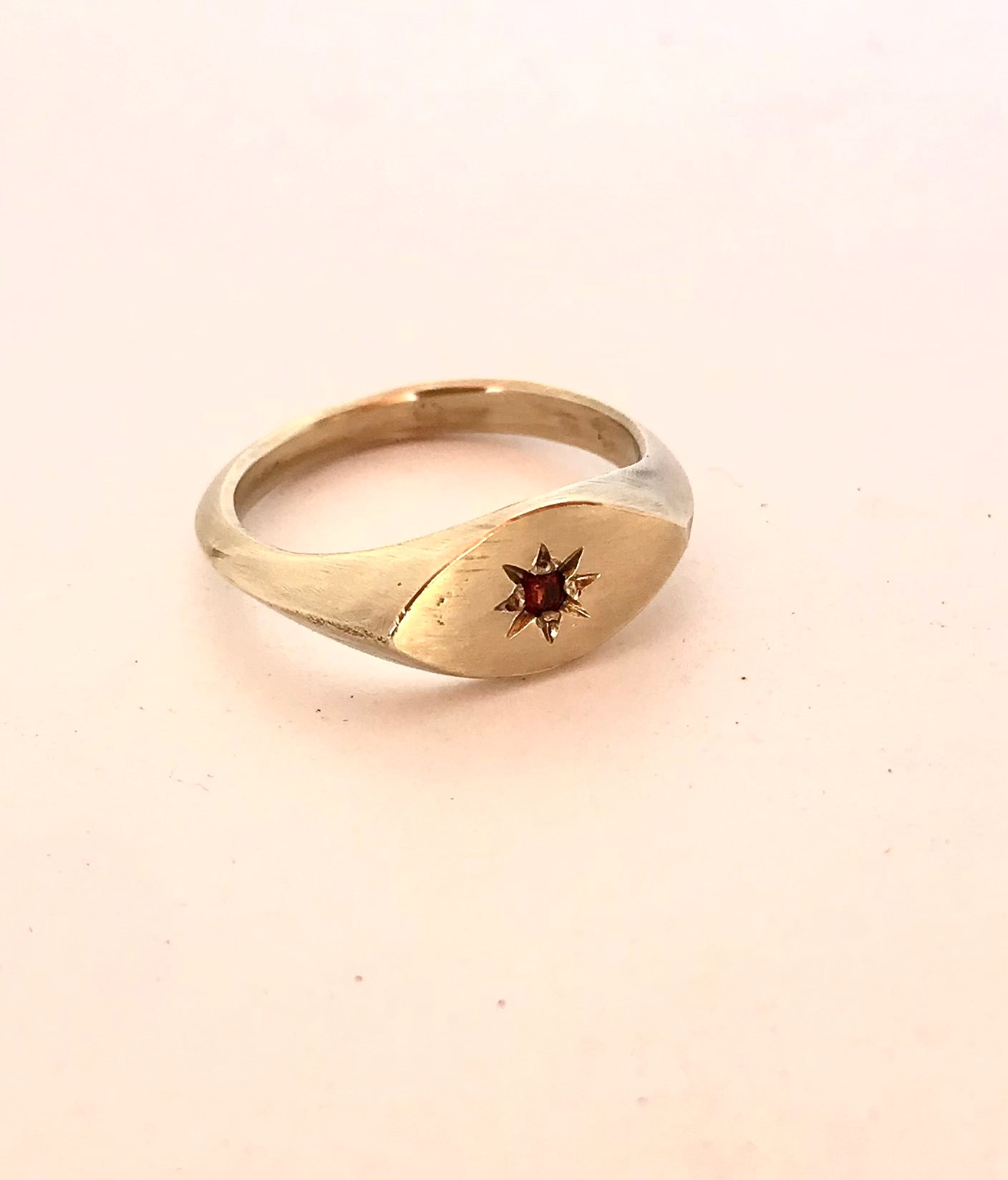 Close-up of the brass signet ring showcasing the star engraving and gemstone setting
