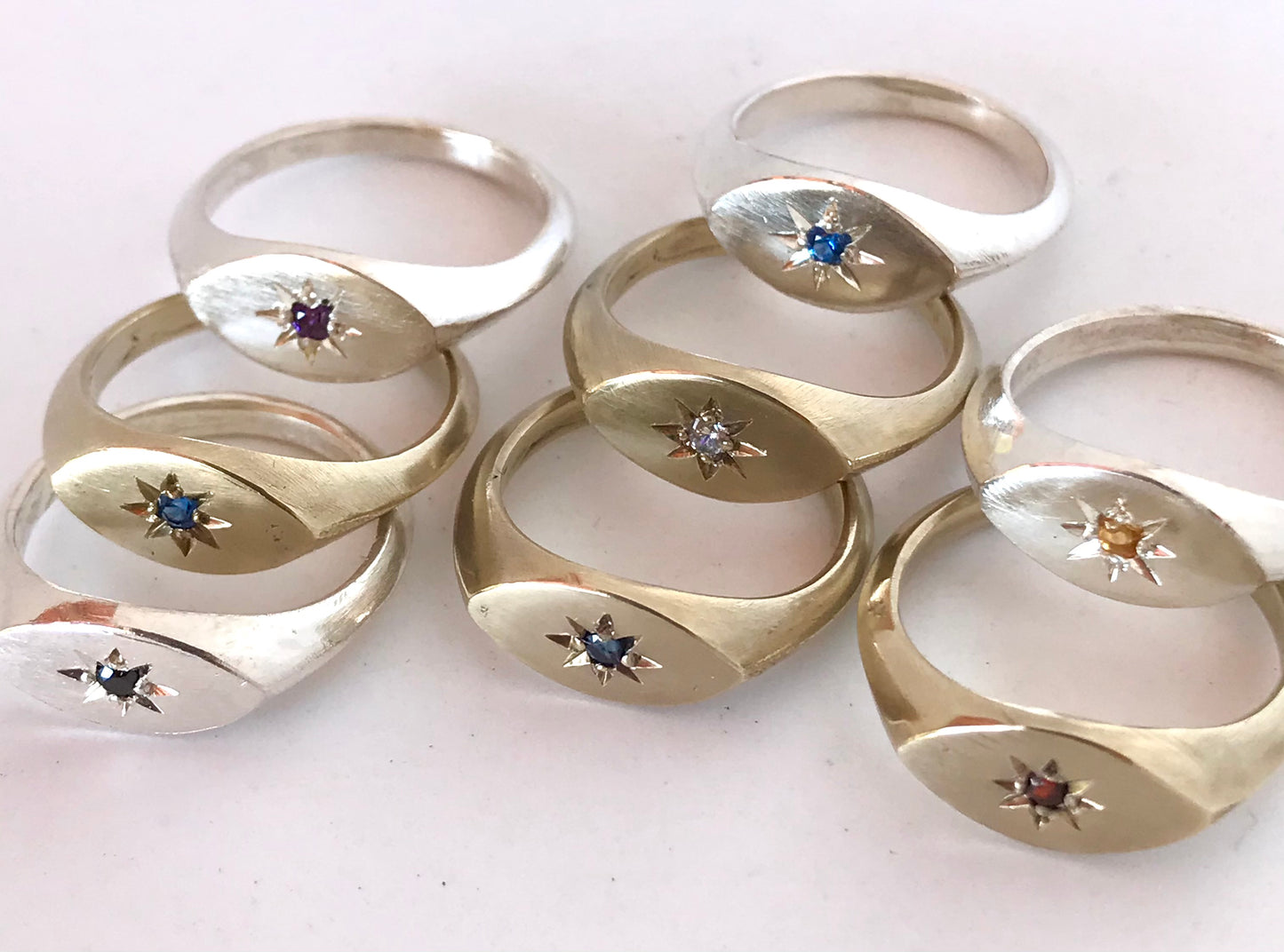 Collection of brass ladies signet rings with various gemstone options displayed in a circle.
