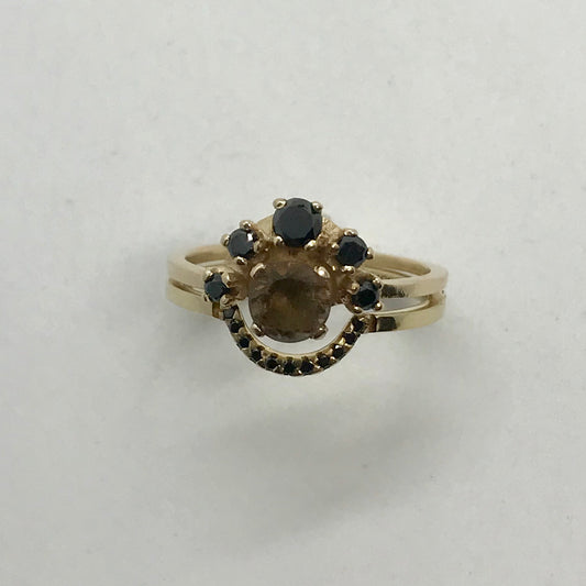 Custom-designed gold ring with a central smokey quartz stone surrounded by black diamonds.