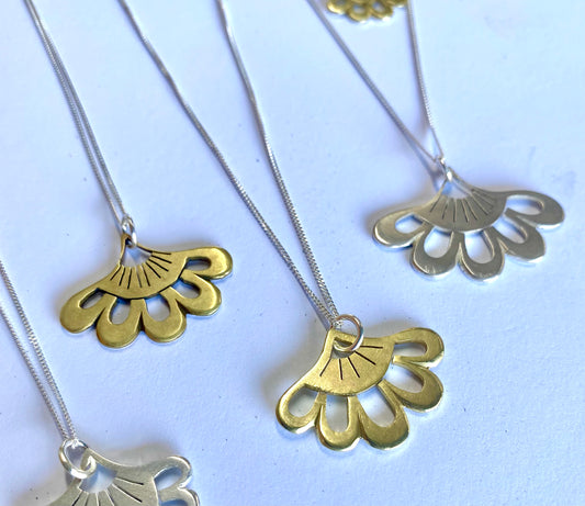 Handcrafted Lotus-inspired pendants in silver and brass, displayed against a white background