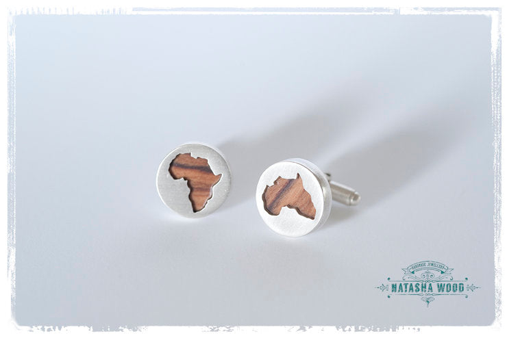 Close-up of handcrafted silver cufflinks with African continent cutout revealing olive wood detail.