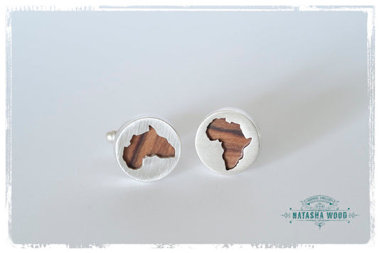 Round sterling silver cufflinks with African continent silhouette in olive wood inset on white background.