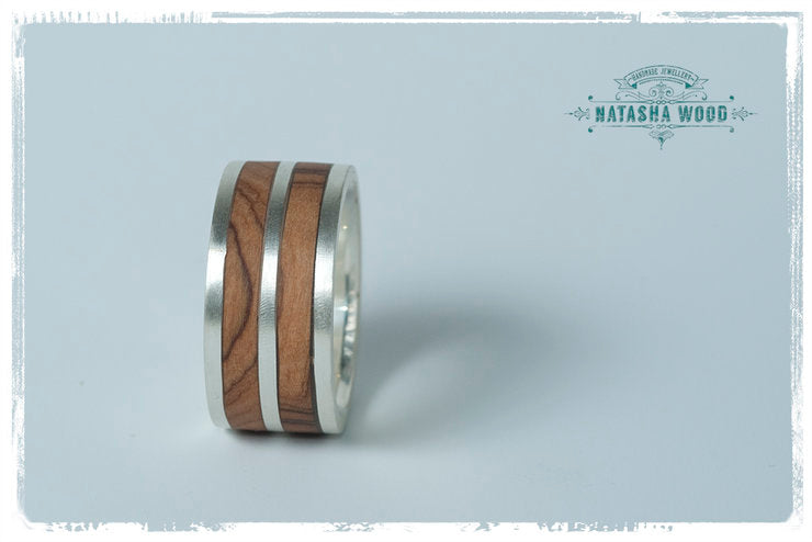 Angled side view highlighting the contrasting layers of wood and silver in the ring