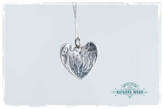 Close-up of the sterling silver Protea Heart Pendant with detailed flower design.