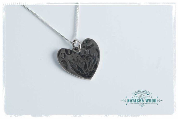 Bright sterling silver Protea Heart Pendant, beautifully displayed on a light background.