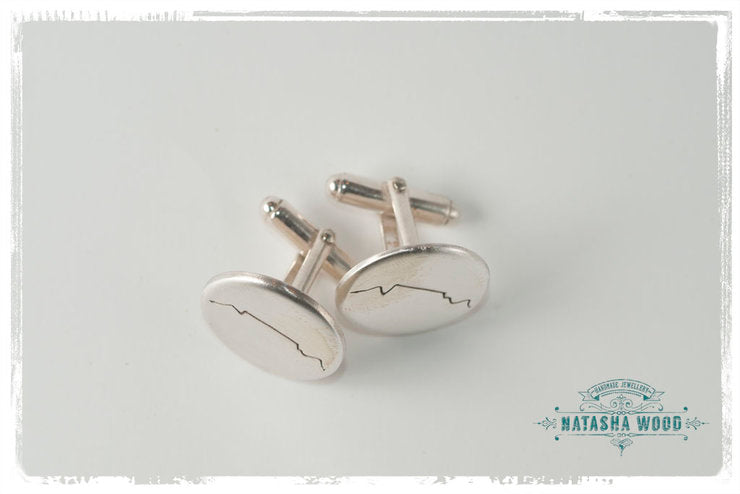 Silver cufflinks with Table Mountain silhouette displayed on their side, showcasing the fastening mechanism.