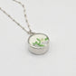 Silver necklace with a round pendant featuring floral design on a light gray background