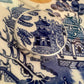 Willow Pattern silver pendant - top-down detail view on antique blue and white Willow Pattern plate