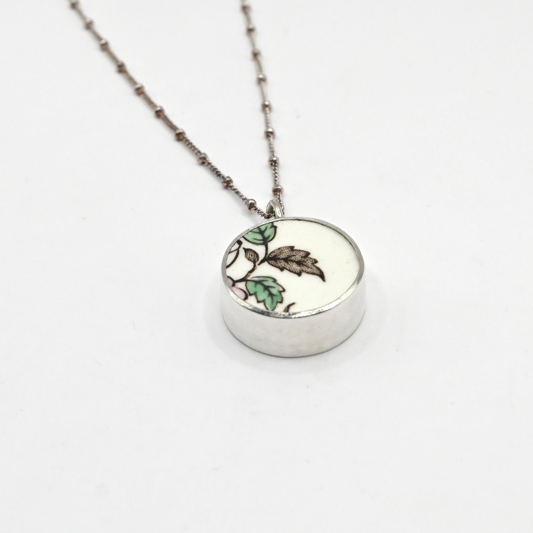 Reversible antique china shard pendant - side angle showing bezel depth and hand-painted floral ceramic face, sterling silver