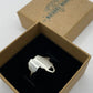 Silver ring with a unique design in a brown box on a white background