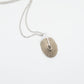 Santa Maria Shell Pendant - angled flat-lay view, brass shell with sterling silver chain