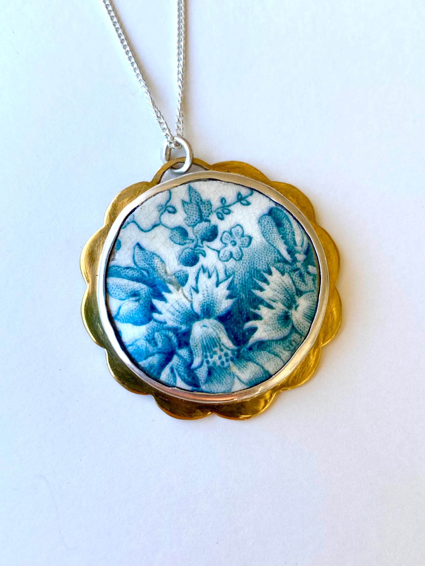 Green floral ceramic set in silver and brass scalloped detail pendant.