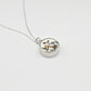 Silver necklace with a round pendant featuring floral design on a white background