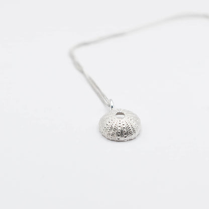 medium Sea Urchin Sterling Silver Pendant - three-quarter side view with chain on white surface