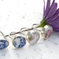 Set of floral-themed rings on a white surface with a purple flower.