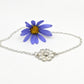 Daisy Flower Bracelet - sterling silver hand-carved daisy on marble surface with yellow daisy prop, angled view