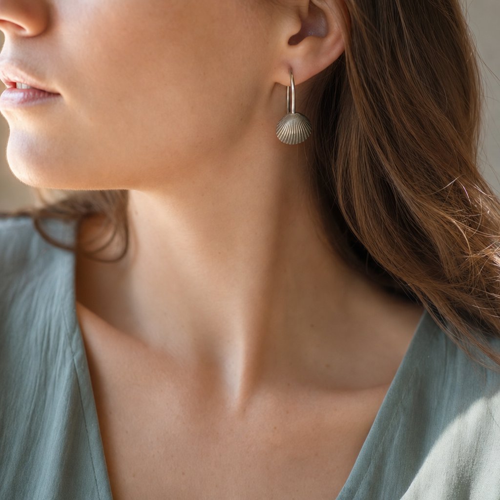 Brass Scallop Shell Earrings - lifestyle shot on coastal rock surface with sterling silver hooks