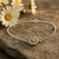 Daisy Flower Bracelet - sterling silver daisy charm bracelet laid diagonally on marble with yellow daisy flower