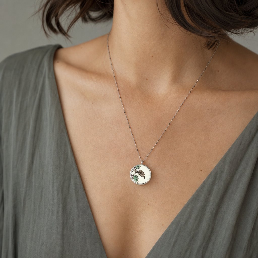 Reversible antique china shard pendant - front view showing hand-painted floral ceramic face, sterling silver, worn by model
