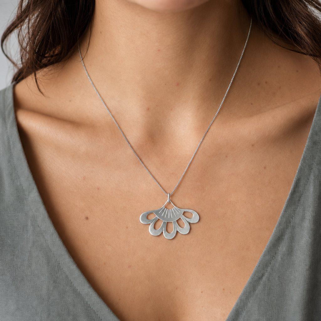 Lotus Flower Pendant - close-up of sterling silver hand-pierced detail on natural wood surface - Natasha Wood Jewellery