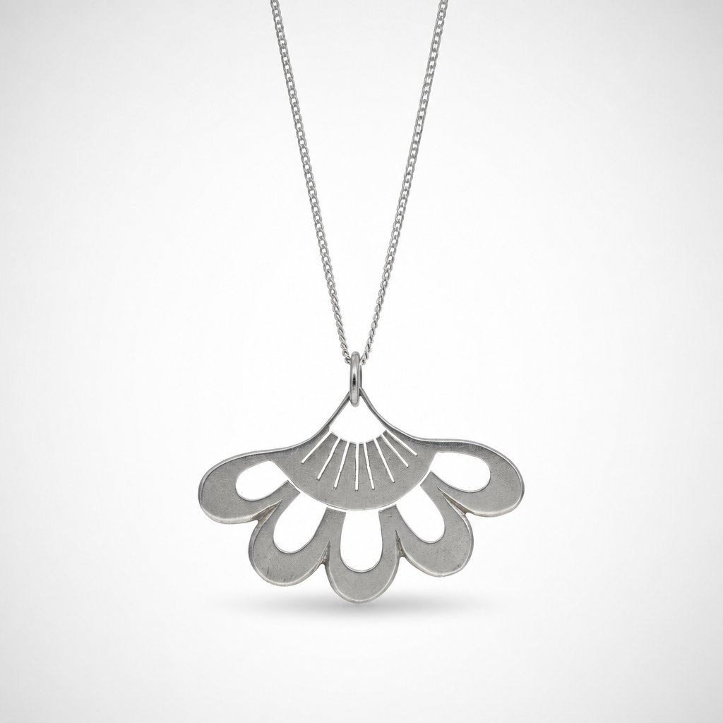 Lotus Flower Pendant - close-up of sterling silver hand-pierced detail on natural wood surface - Natasha Wood Jewellery