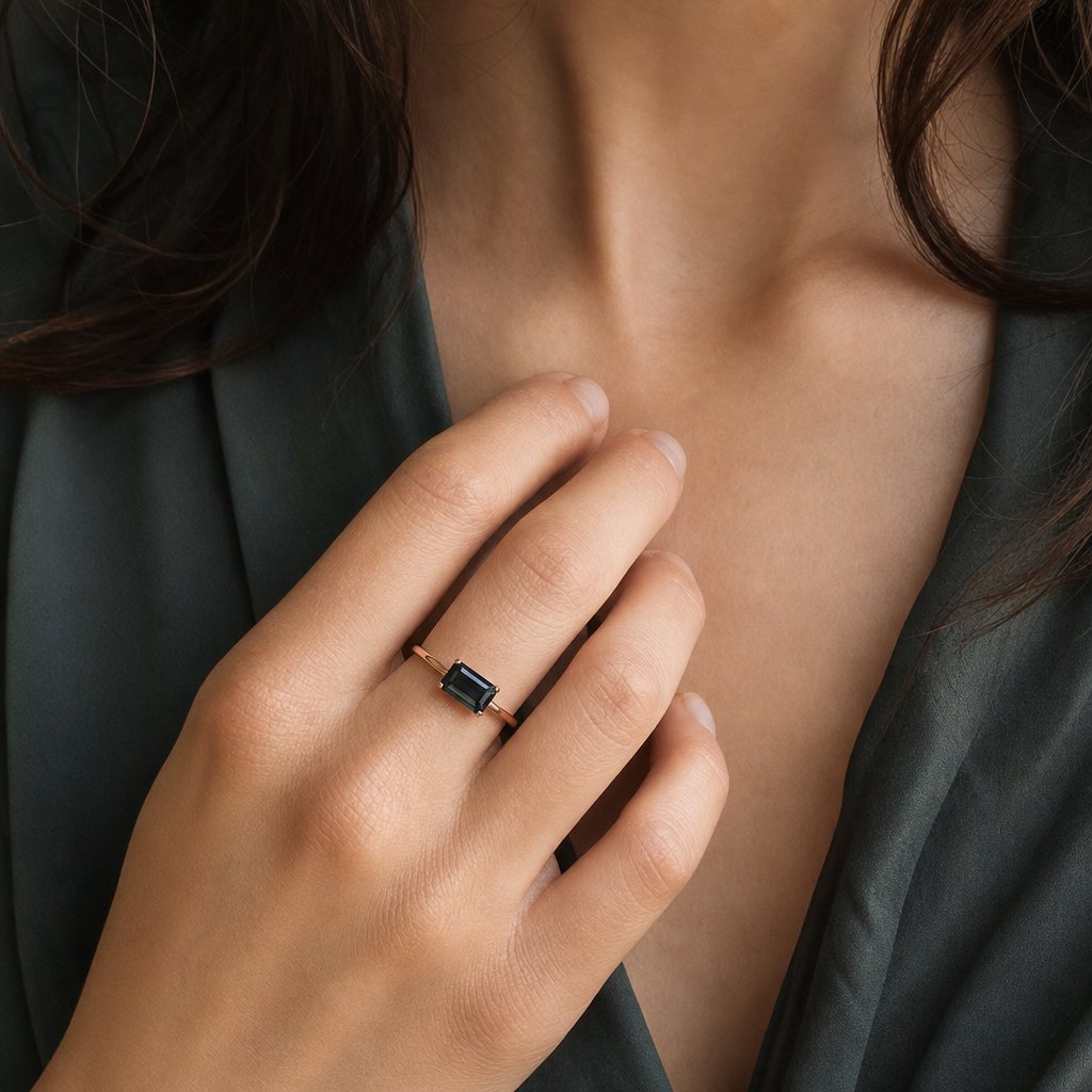 Bespoke rose gold ring with emerald-cut black diamond - four-claw solitaire on white fabric background