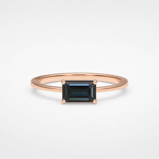 Bespoke rose gold ring with emerald-cut black diamond - four-claw solitaire on white fabric background