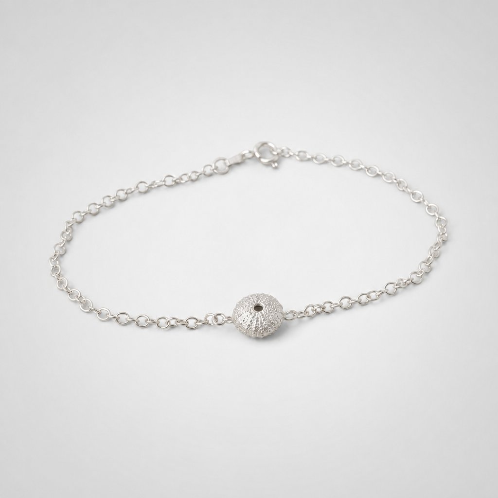 Sterling Silver Sea Urchin Bracelet - flat lay on coastal rock texture
